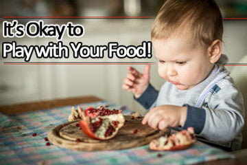 Toddler in high chair eating food with fingers.